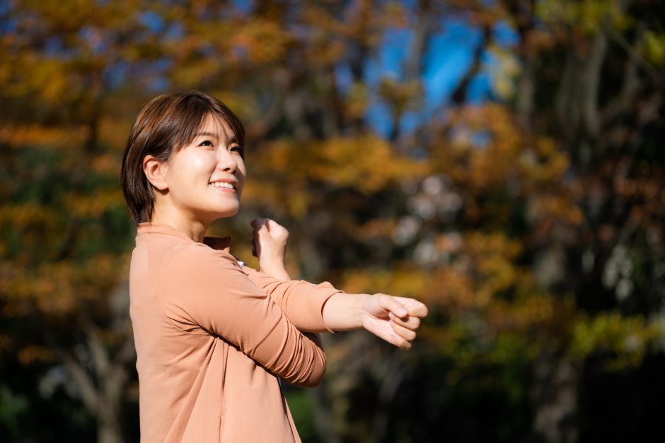 秋の景色の中で、ストレッチする女性