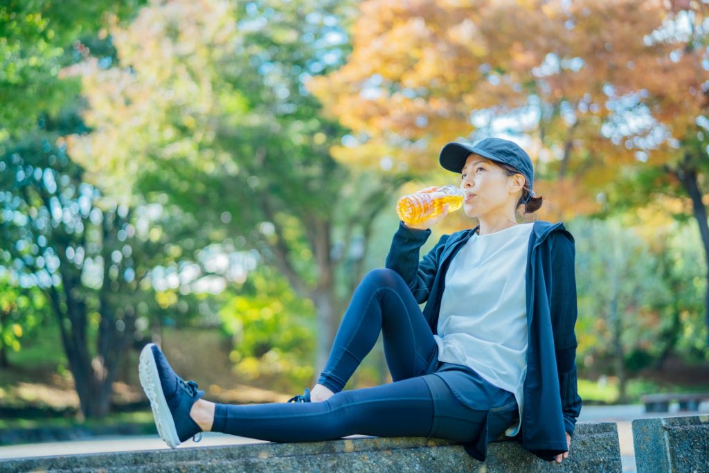 紅葉の中で水分補給をする女性